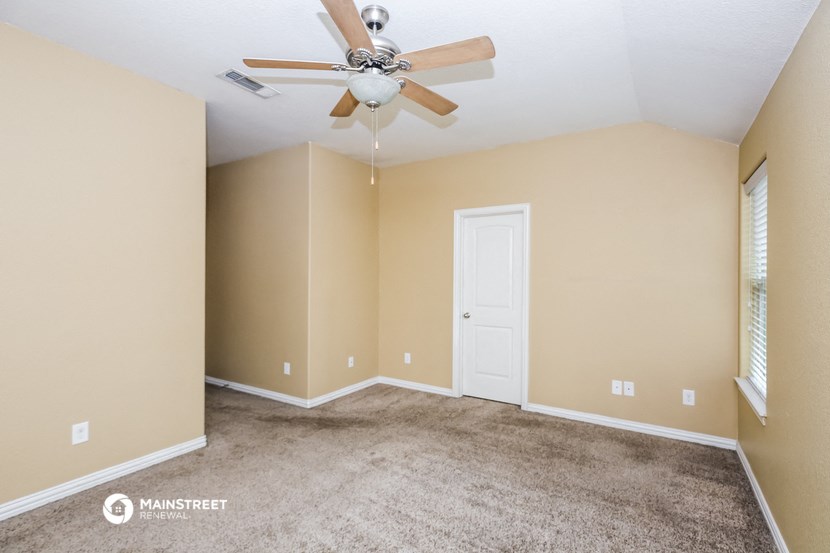 the spacious living room with carpet and a ceiling fan