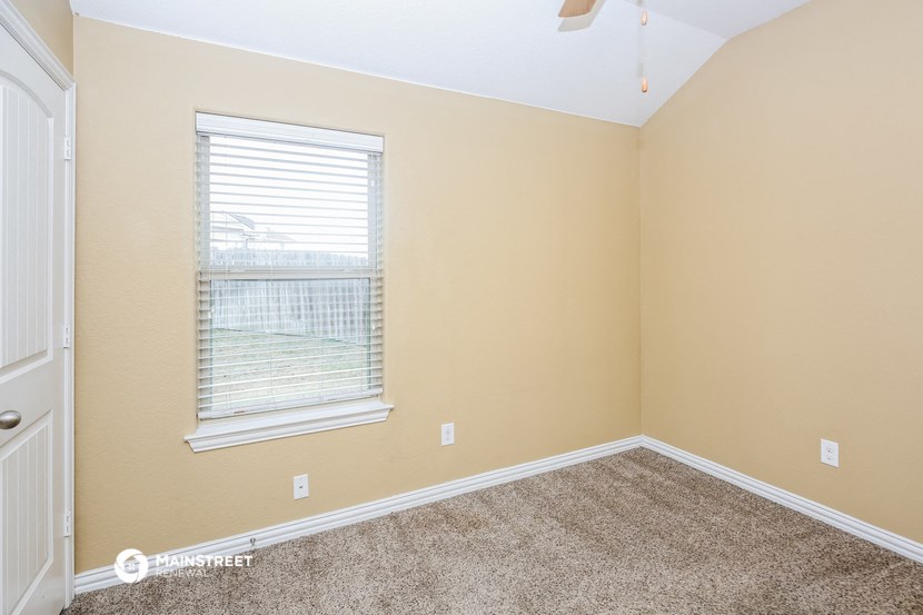 the bedroom of a house with carpet and a window