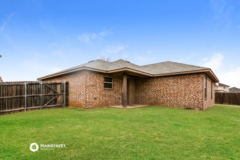 a small brick house with a yard and a wooden fence