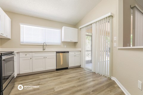 a kitchen with white cabinets and a door to a balcony