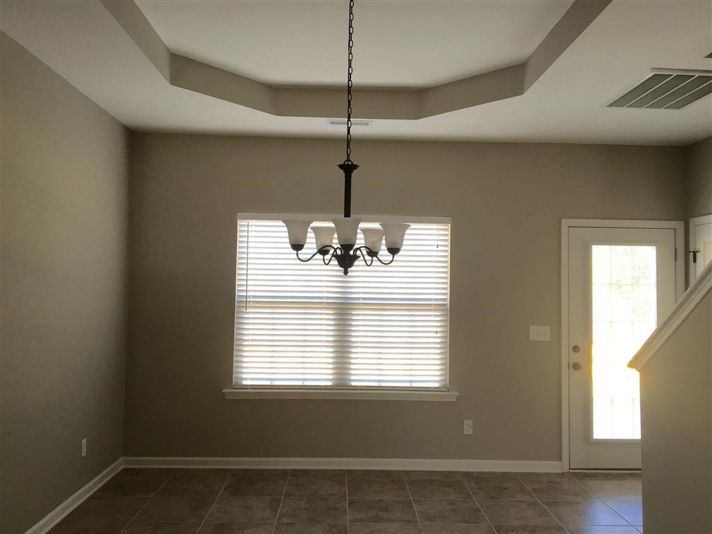 an empty living room with a window and a chandelier
