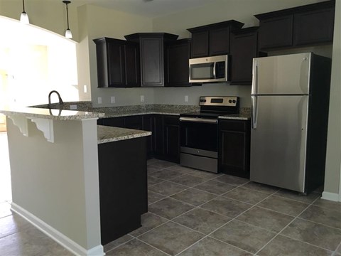 a kitchen with black cabinets and stainless steel appliances