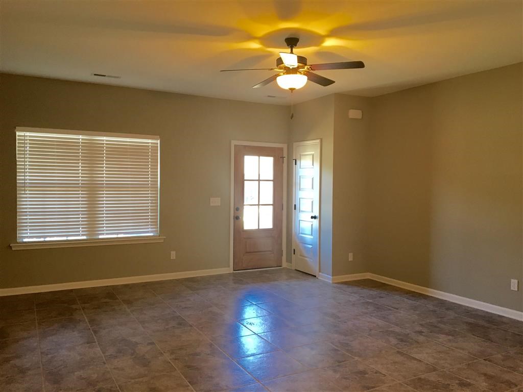 a empty living room with a ceiling fan and tiled floor
