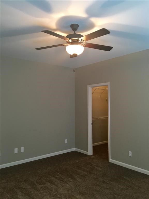 a bedroom with a ceiling fan and a door to a closet