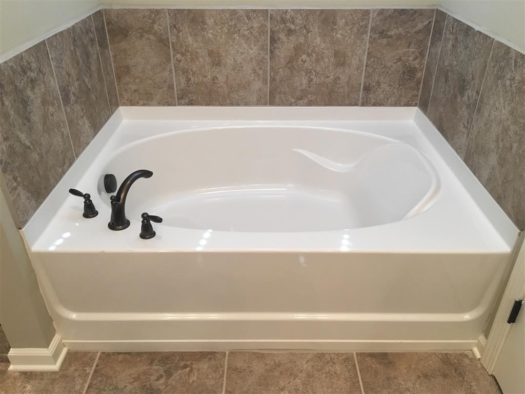 a large white bath tub in a tiled bathroom