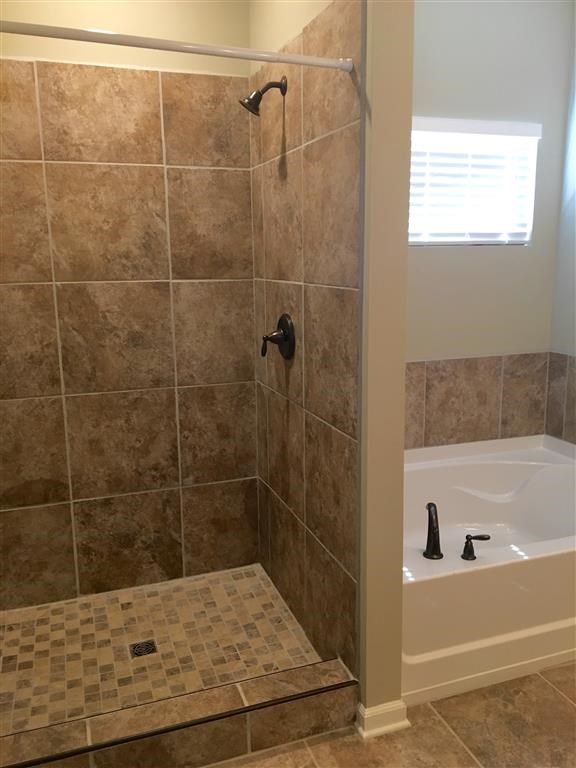 a tiled bathroom with a tub and a shower