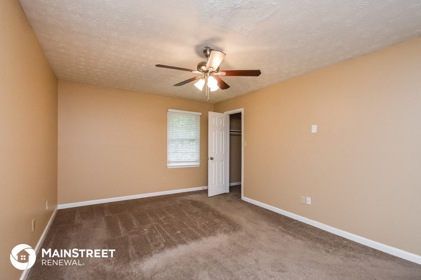 the spacious living room has carpet and a ceiling fan