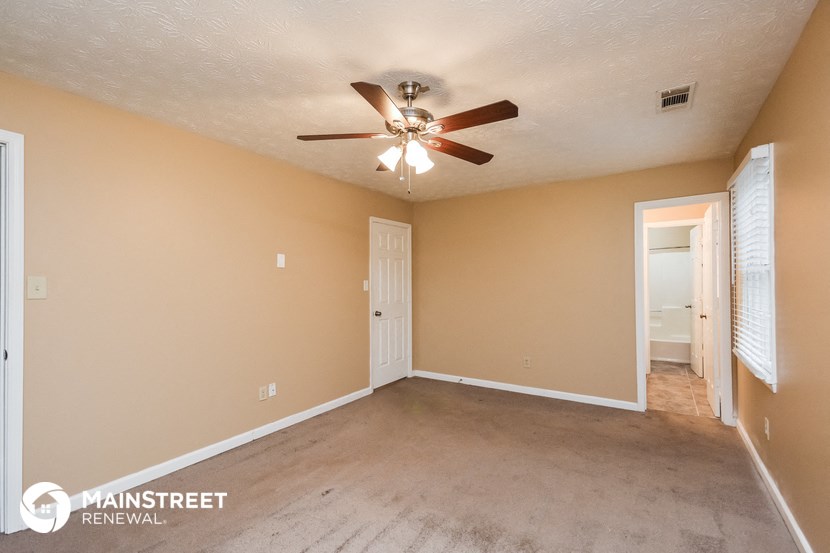 the spacious living room with carpet and a ceiling fan