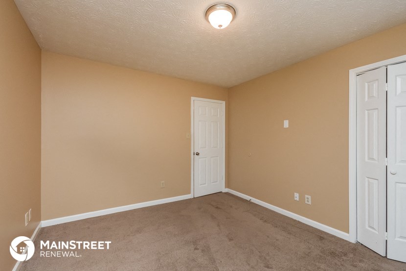 the spacious living room with two doors and carpeted flooring