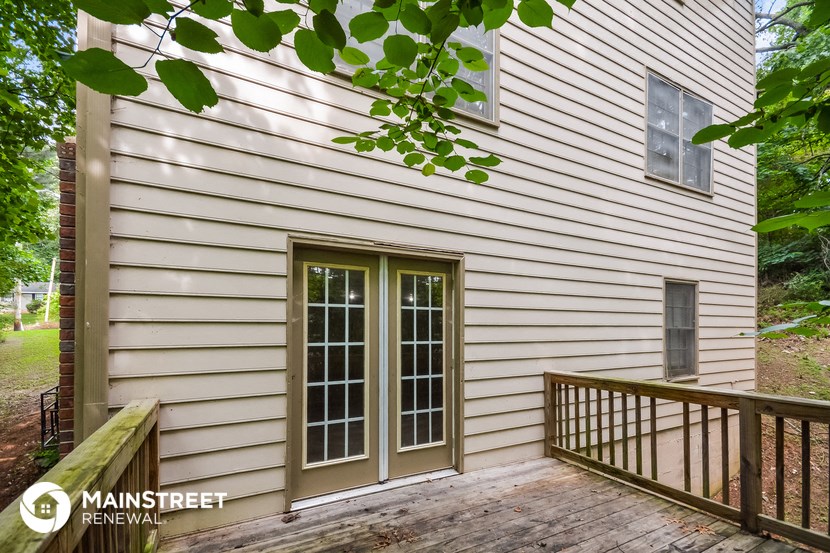 the front of a house with white siding and a wooden deck