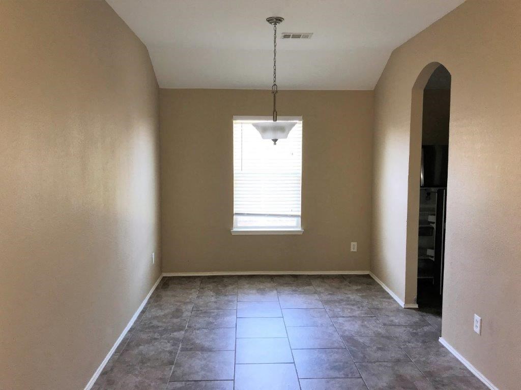an empty living room with a window and tiled floors
