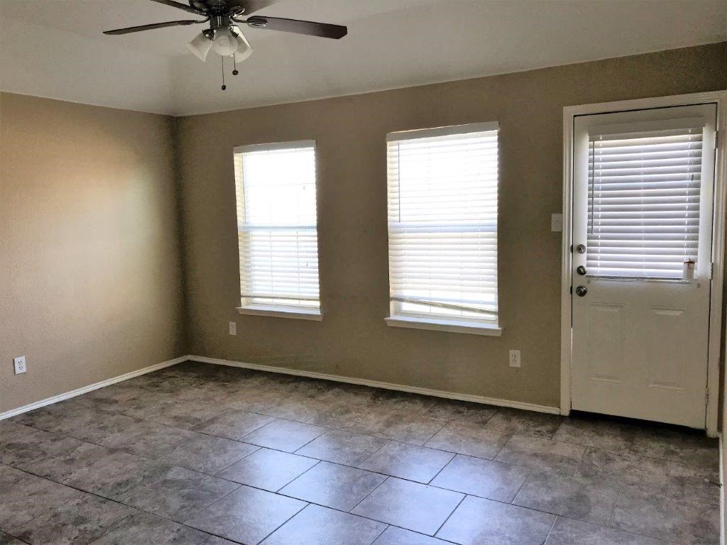 an empty room with a ceiling fan and three windows