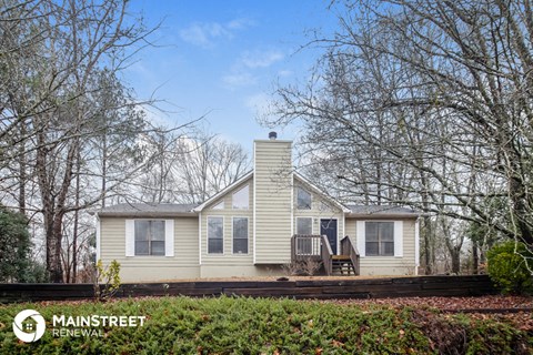 a small white house with a deck and trees