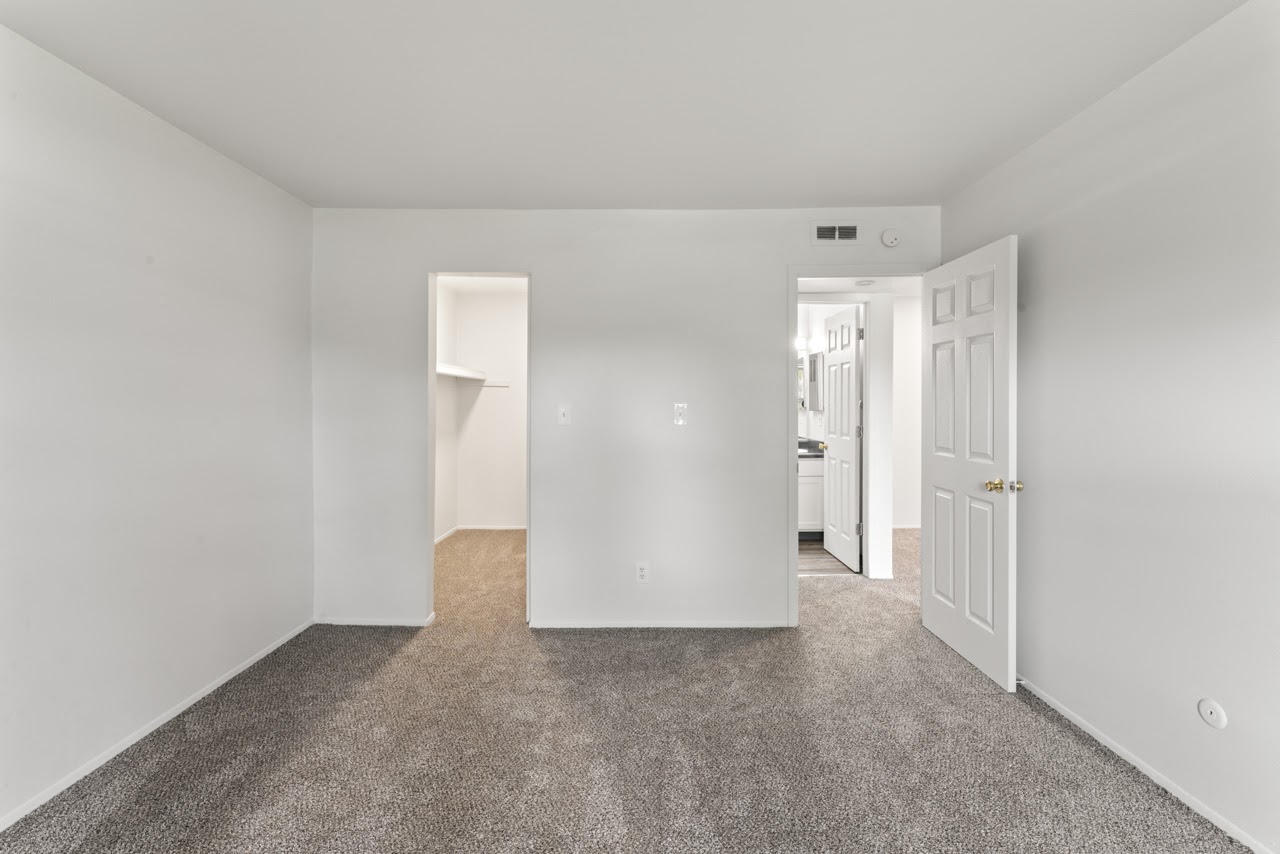 a living room with white walls and carpet and a white door