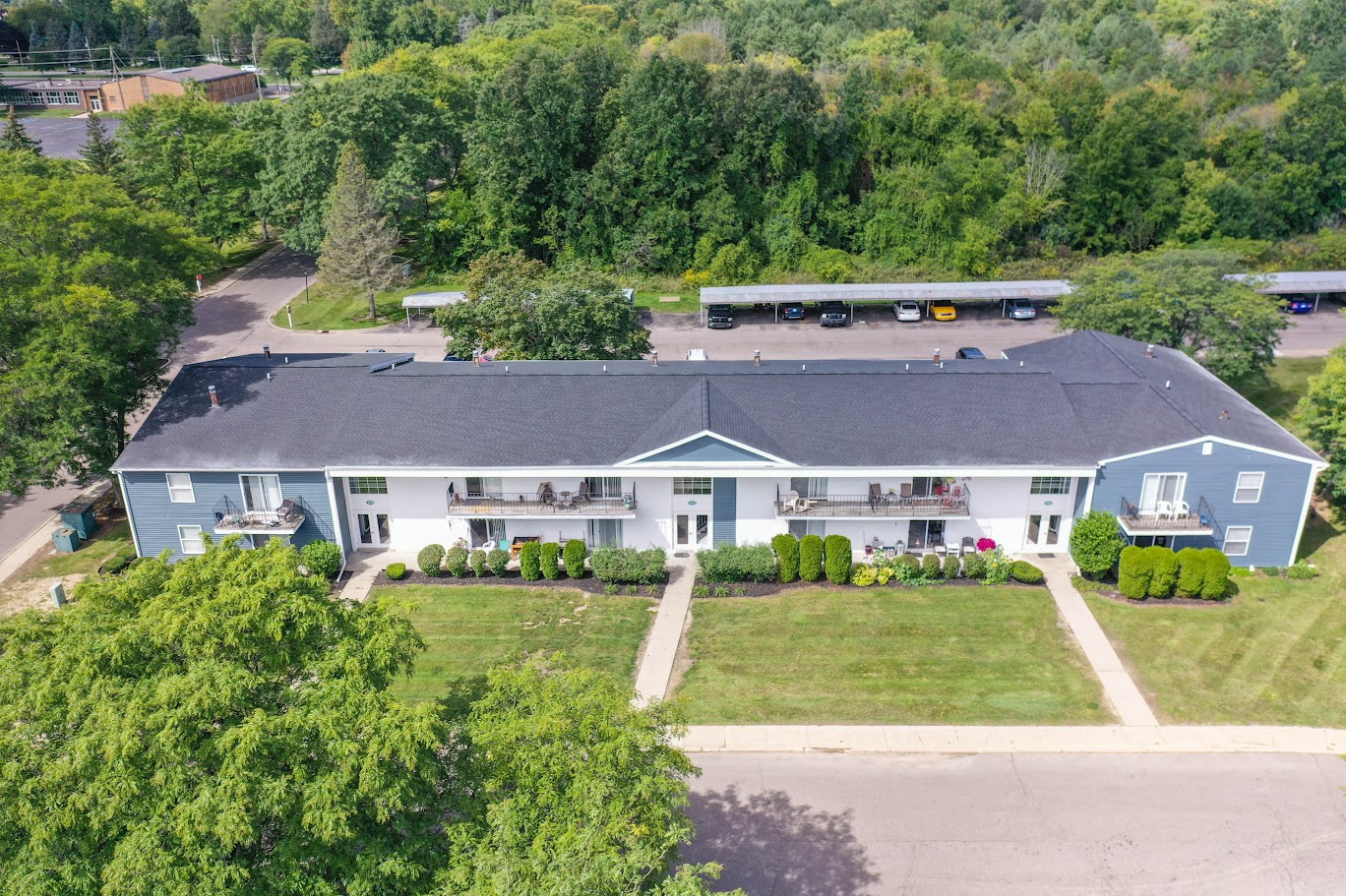 a white and blue house with a gray roof and a green yard