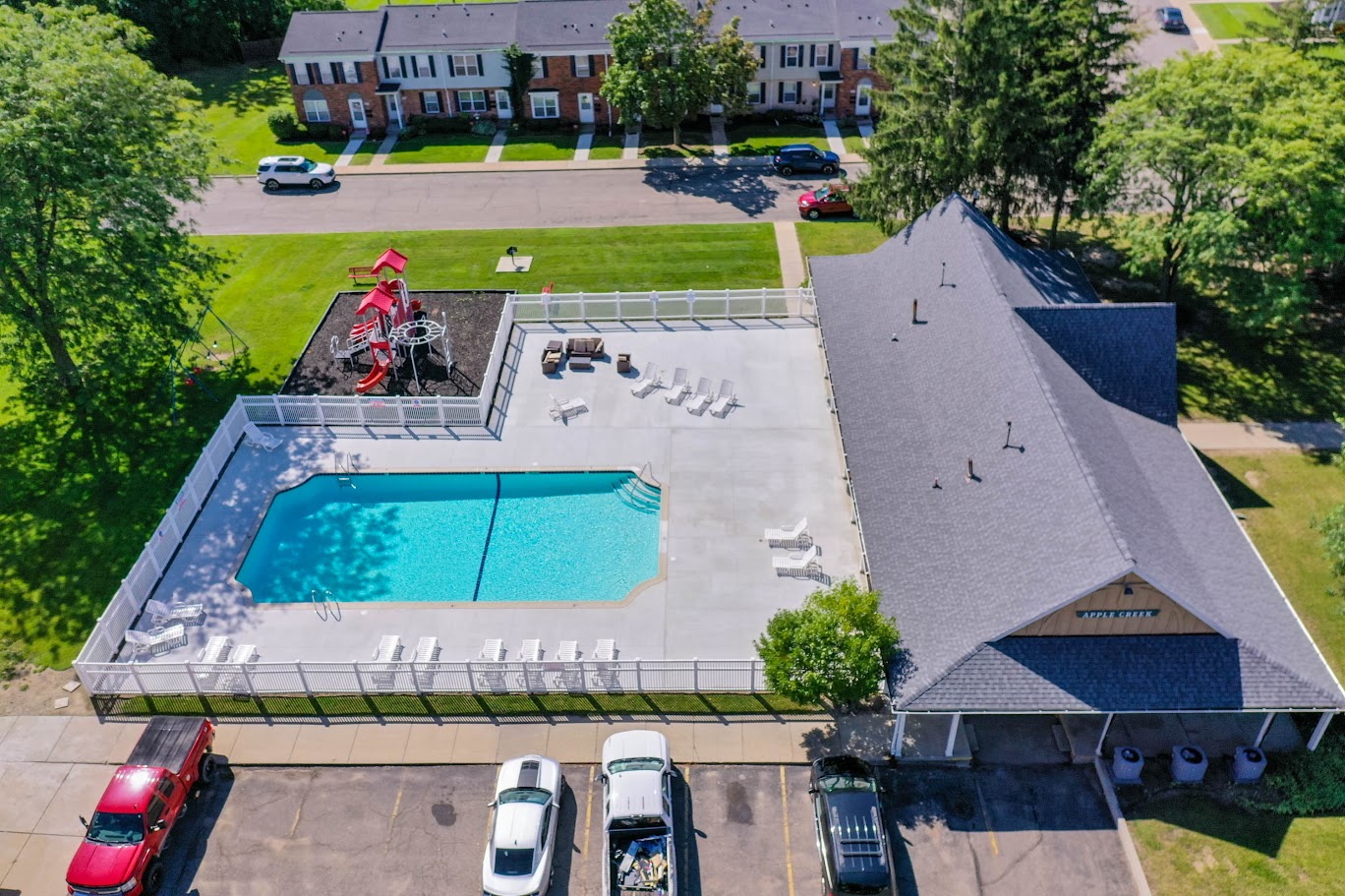 an aerial view of a swimming pool and a parking lot with a building and cars