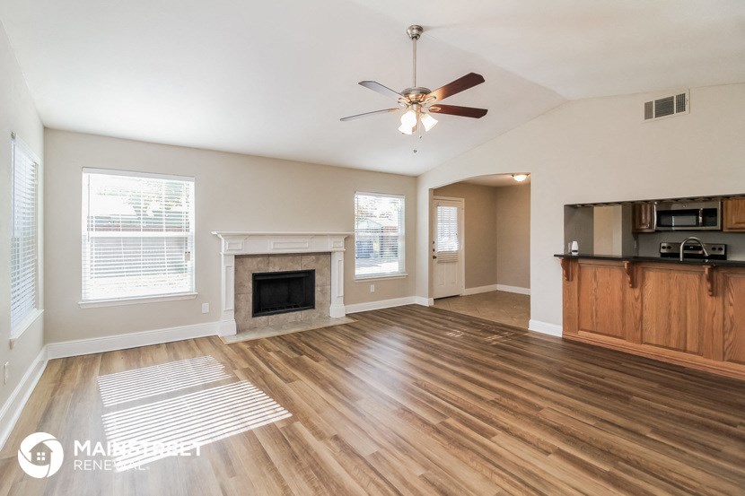 a living room with a fireplace and a ceiling fan