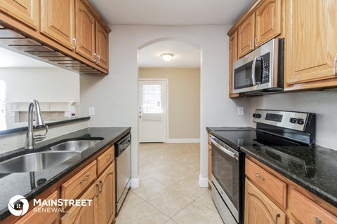 a kitchen with black counter tops and wooden cabinets and a sink and a microwave