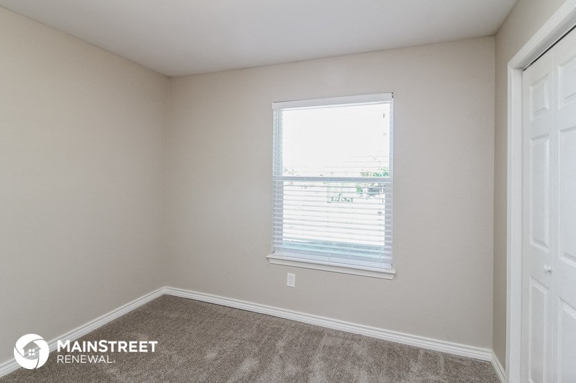 the bedroom of a rental home with a window and carpet