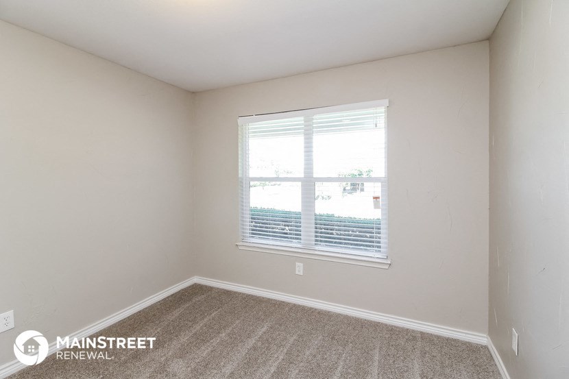 a bedroom with a large window and a carpeted floor