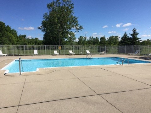 a swimming pool with white chairs around it