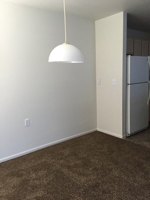 an empty room with a refrigerator and a lamp