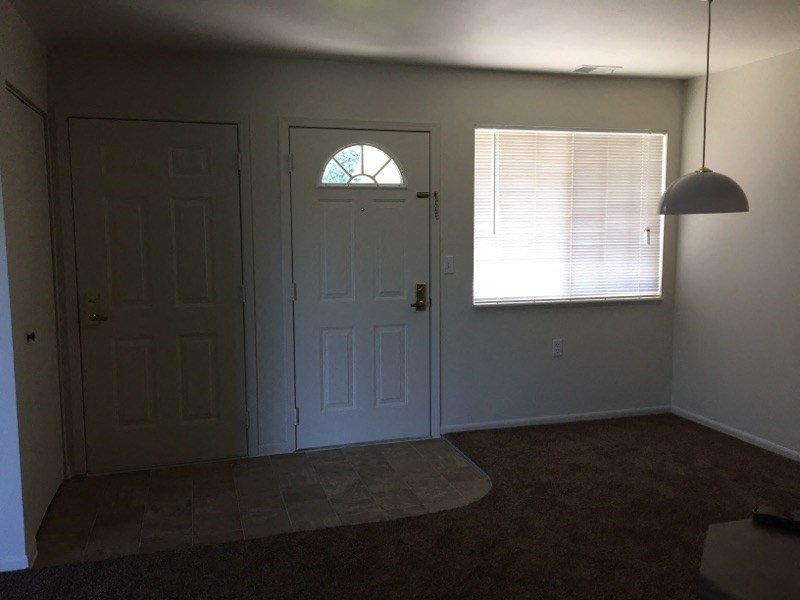 an empty living room with a door and a window
