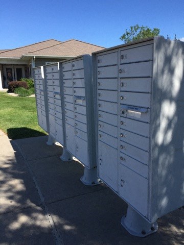 a row of mailboxes on a sidewalk in front of a house