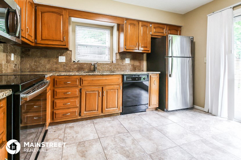 a kitchen with wooden cabinets and a black refrigerator