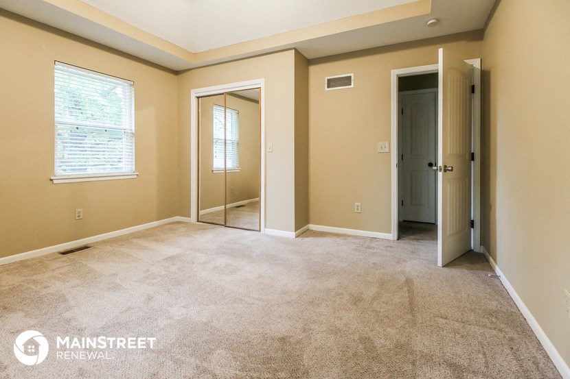 a master bedroom with a carpeted floor and a door to a closet