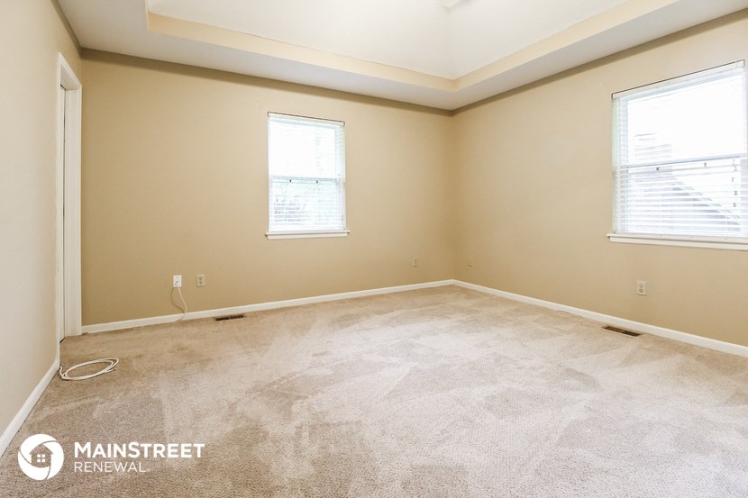 the bedroom of a home with carpet and two windows
