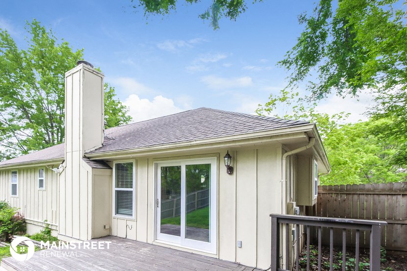 a small white house with a deck and a window