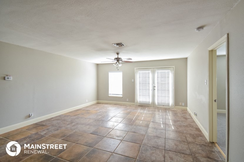 the spacious living room with tile flooring and a ceiling fan