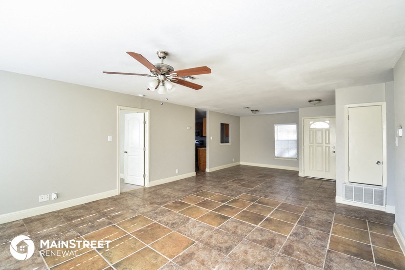 an empty living room with tile flooring and a ceiling fan