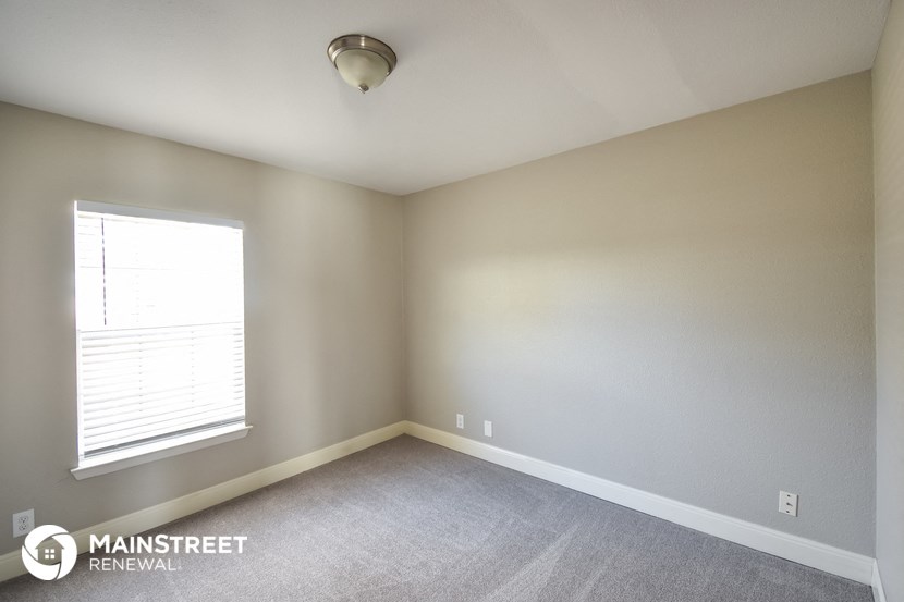 the upstairs bedroom has a large window and carpeted floors