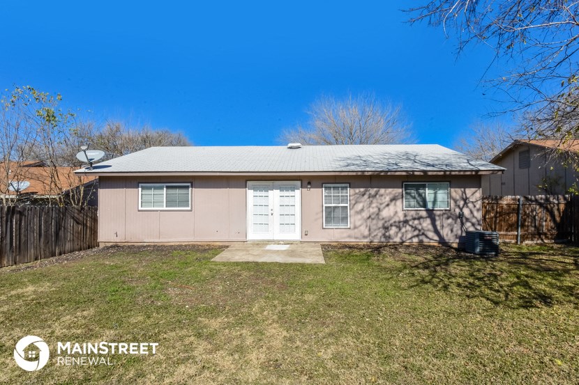 a small pink house with a yard and a white door