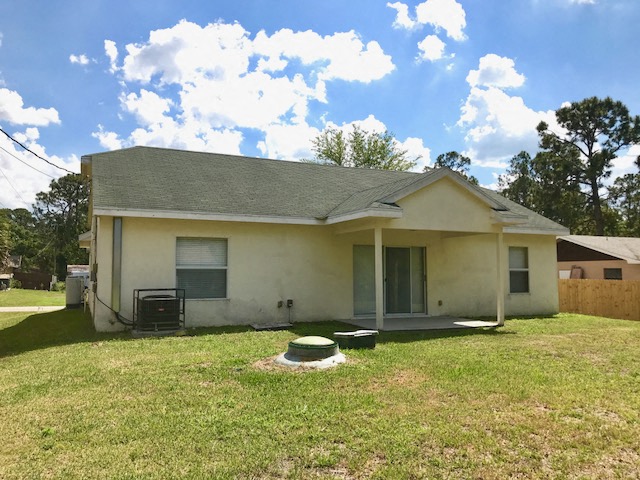 a white house with a grass yard and a blue sky