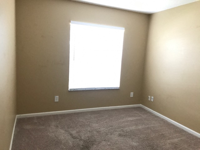 an empty room with a window and a carpet