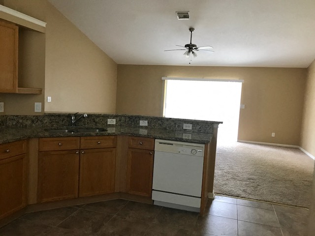 an empty kitchen with a white stove and a ceiling fan