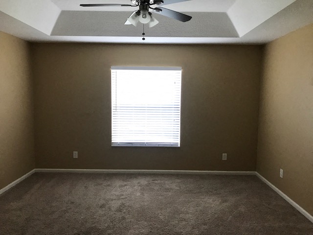 an empty room with a ceiling fan and a window