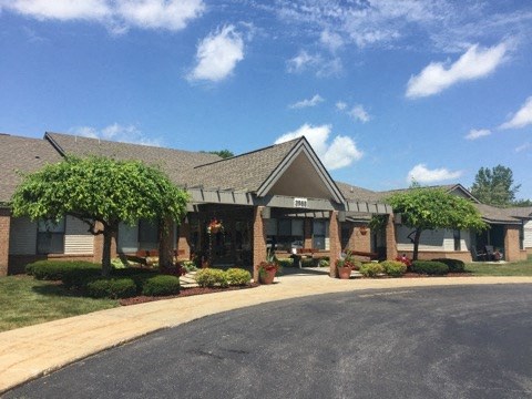a view of the front of a brick building with trees and a driveway