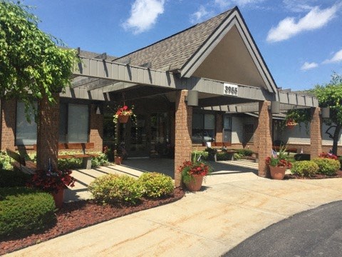 the front of a building with potted plants and a sidewalk