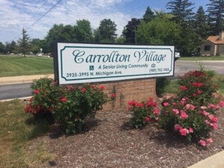 a sign on the side of a road in front of some flowers