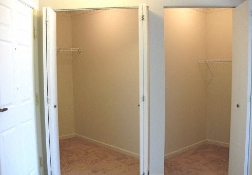 an empty bathroom with a closet and a white door