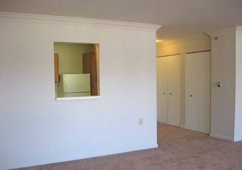 an empty living room with a mirror in the wall