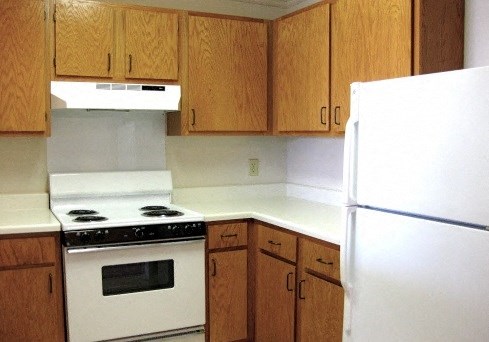 a kitchen with white appliances and wooden cabinets