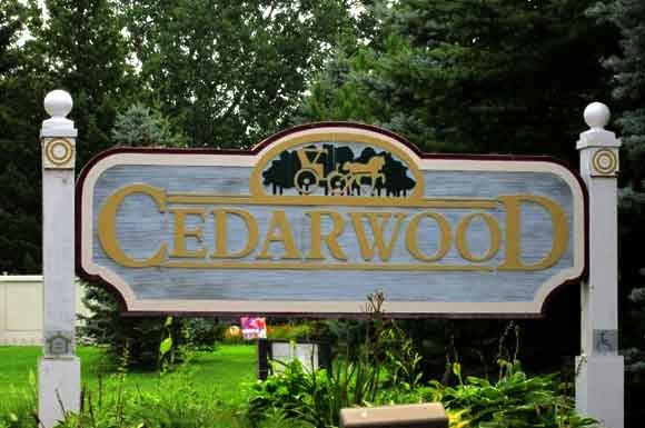 a sign for cedarwood in front of a green field
