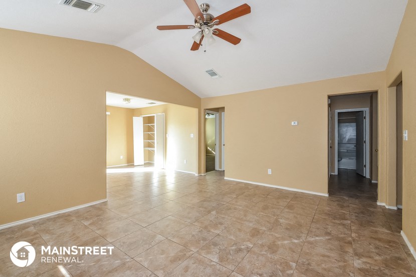 the spacious living room with tile flooring and a ceiling fan