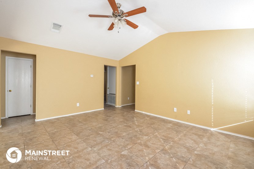 the spacious living room with tile flooring and a ceiling fan