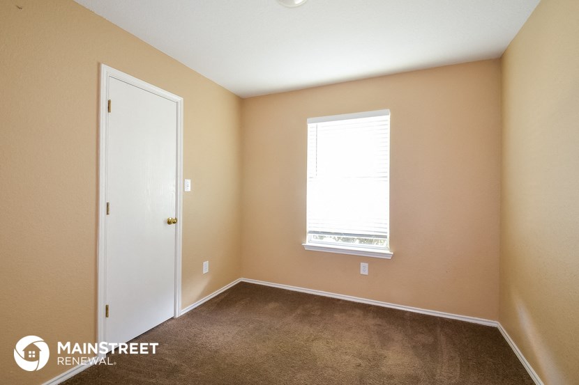 a bedroom with carpet and a window and a door